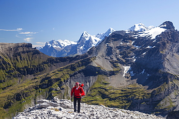 A man hiking on the ridge between Schwarzhorn and Bundstock high above Kiental, view to Wetterhorn, Eiger, Moench, Jungfrau, Bernese Oberland, Canton of Bern, Switzerland