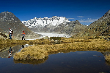 Hiking couple at lake Bettmersee, Bettmeralp, in the background Bernese Oberland, Canton of Valais, Switzerland, Europe