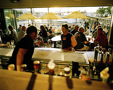 View fron the counter at people inside the Bar for yachtsmen in the evening, Viaduct Harbour, Auckland, North Island, New Zealand