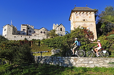 Couple on electric bikes in front of Kastelbell castle, E-bikes, Bozen, South Tyrol, Italy