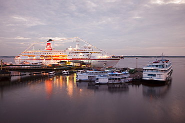 Cruise ship MS Deutschland (Reederei Peter Deilmann) and Amazon river boats at dusk, Manaus, Amazonas, Brazil