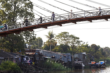 Stilted houses and suspension bridge over Mekong canal, Long Xuyen, An Giang Province, Vietnam