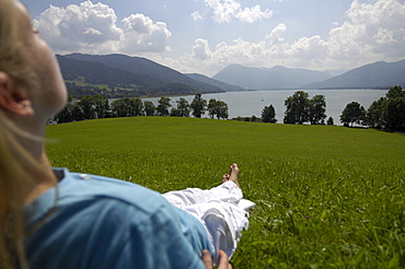 Young woman lying in the grass, near lake Tegernsee, Upper Bavaria, Bavaria, Germany