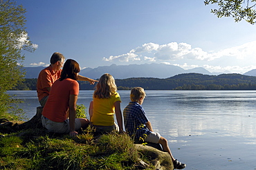 Family sitting on the shore of lake Staffelsee, near Murnau, Upper Bavaria, Bavaria, Germany