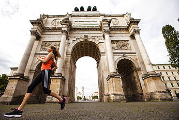 Female jogger passing Siegestor (vitory gate), Munich, Bavaria, Germany