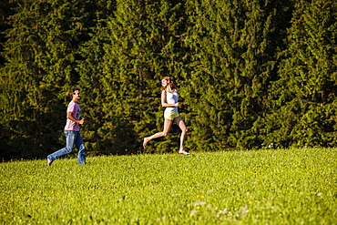 Couple running over a meadow, Upper Bavaria, Germany