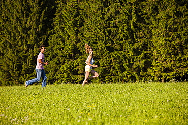 Couple running over a meadow, Upper Bavaria, Germany