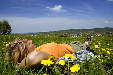 Woman lying in a meadow, hiking tour near Tabarz, near Eisenach, Thuringia, Germany