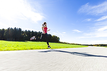 Woman jogging along a road, Munsing, Bavaria, Germany