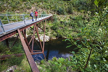 Couple standing on an old railway bridge over the Thomson River, Walhalla, Victoria, Australia