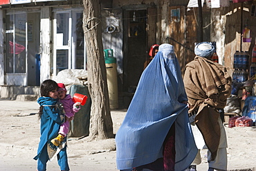 Girl and child follow their mother wearing a burqa on a Kabul street, , Afghanistan