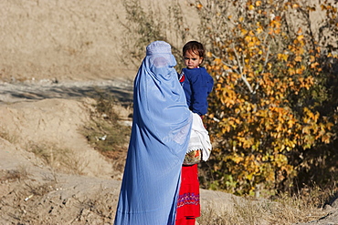 Afghan woman wearing a burqa holding a girl along the Kabul-Charikar Road, Parwan Province, Afghanistan