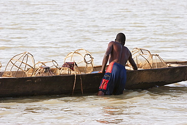 Fisherman and his nets on a boat in Lake DâˆšÂ©bo, formed by the seasonal flooding of the Niger River, Mali