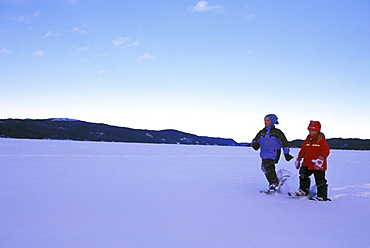 Young Girls Snowshoe across Snow Covered Lake, Northern Ontario