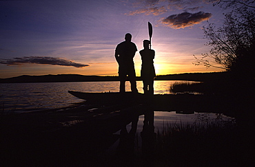 Couple Silhouetted by Sunset Standing beside a Kayak, Yukon