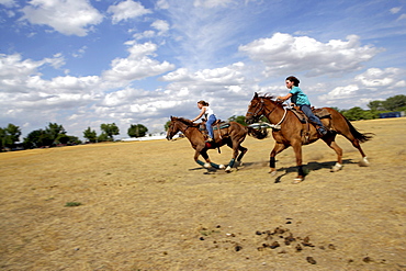 Galloping past at full speed on horses, Val Marie, Saskatchewan.