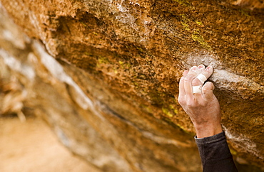 Mans Hand Clinging to Rock while Climbing