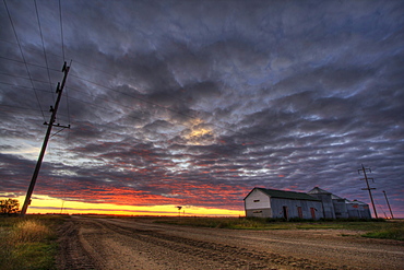 Grain silos and farm buildings during a fall sunset north of Legal, Alberta.