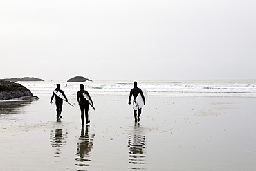 Three Surfers Walk on Beach Toward the Surf, Tofino, British Columbia