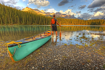 Man standing beside his canoe at sunset, Maligne Lake, Jasper National Park, Alberta