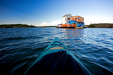 Kayaker approaching colourful houseboats, Yellowknife Bay on the Great Slave Lake, Yellowknife, Northwest Territories