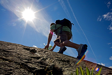 Man hiking along a steep, rocky section of the Great Slave Lake shoreline, Yellowknife, Northwest Territories