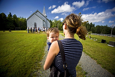 Mother carrying her young boy towards a small Catholic church in Merland, Antigonish County, Nova Scotia