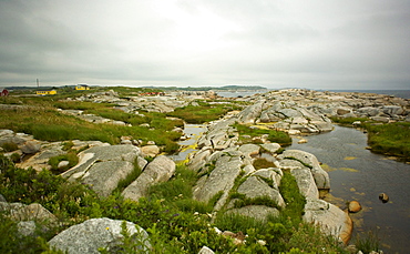 Rocks along the coastline with colourful houses in the background, Peggy's Cove, Nova Scotia