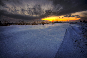 Sunrise over snow drifts and wheat stubble on the Alberta prairies