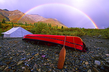 Canoe and Tent at a Campsite with a Rainbow and the MacKenzie Mountains in the Background in Autumn, Snake River, Whitehorse, Yukon