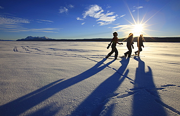 Snowshoers in bright winter sun on the frozen Teslin Lake, Yukon