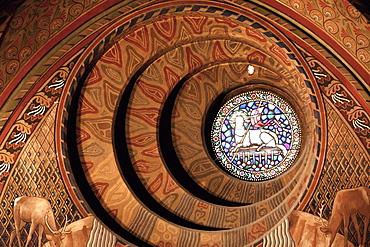 The round window behind the Neo-Roman baptising fountain designed by Schulek shows a scene from the Apocalypse of St John: the Lamb of God and the sealed book at the Mutyus-templom (Matthias Church), Budapest, Hungary