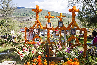 People decorate the grave of four children who died in a house fire for the celebration of Dia de los Muertos, the Day of the Dead at the Tzintzuntzan cemetery. People decorate the graves of their dead children, often referred to as little angels (angelitos) with offerings of flowers, particularly marigolds (cempoalxochitl or zempasuchil), bread of the dead (pan de muerto), candles, toys, the deceased's favourite food, drinks and personal belongings to guide their spirits home., Michoacun, Mexico