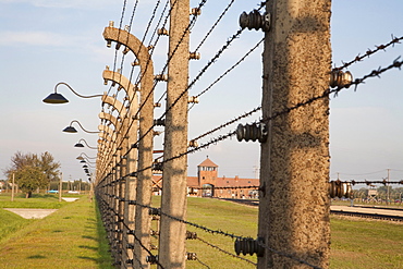 View of the Main Guard House through the electrified barbed wire fence separating sections of the Auschwitz-Birkenau Concentration Camp, Oswiecim, Malopolska, Poland