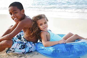 Hawaii, Oahu, Lanikai, Two Children with inflatable toy relax at beach.