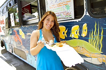 Hawaii, Oahu, Brunette woman eating plate lunch at shrimp truck.