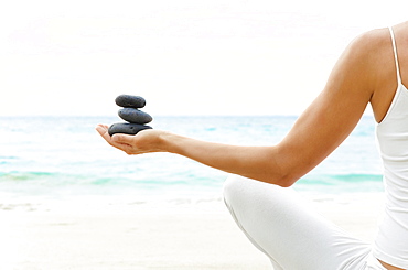 Hawaii, Woman holding stack of stones in hands, Ocean in background.