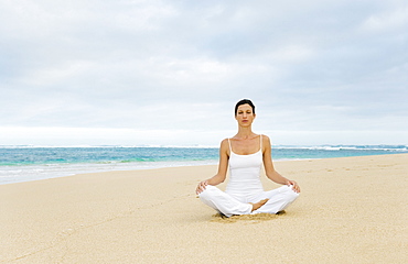 Hawaii, Woman meditating on quiet beach.