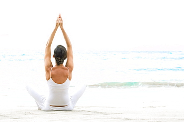 Hawaii, Woman meditating on ocean shore.