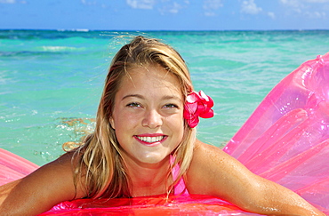 Hawaii, Teenage girl in ocean with inflatable.