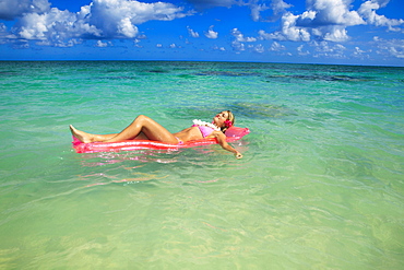 Hawaii, Teenage girl in ocean with inflatable.