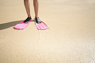 Hawaii, Woman wearing pink snorkel flippers on sandy beach.