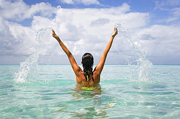 Woman splashing in tropical ocean water.