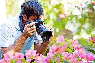 Hawaii, Maui, Male photographer taking pictures of bougianvilleas.