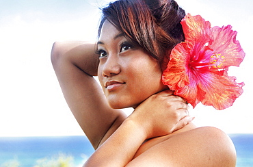 Hawaii, Oahu, Beautiful headshot of a young girl with a hibiscus in her ear.