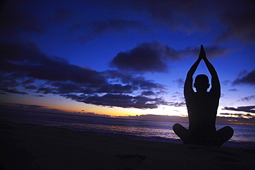 Hawaii, Oahu, Fit young guy on the beach doing yoga on the coastline.