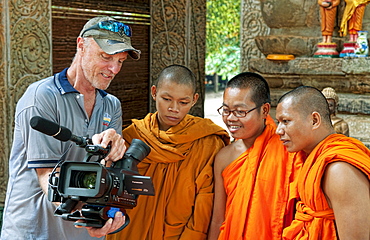 South East Asia, Cambodia, Siem Reap, Bhuddest Temple, Videographer shows video footage to three young monks.