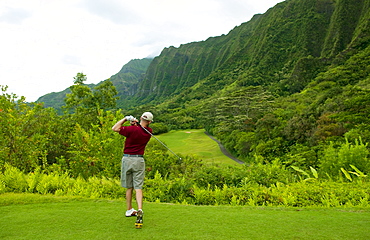 Hawaii, Oahu, Honolulu, Ko'olau Golf Course, Man tees off at the fifteenth hole.