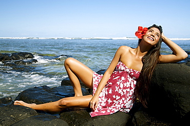 Hawaii, Kauai, Anini beach, Attractive young woman on the rocks with hawaiiana attire.