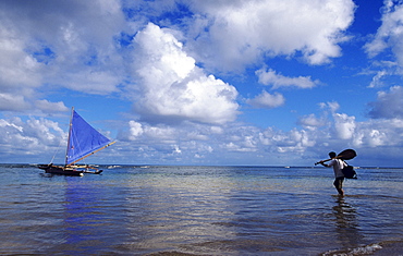 Hawaii, Kauai, Hanalei Bay, Man with paddle wading out into water to sailing canoe.